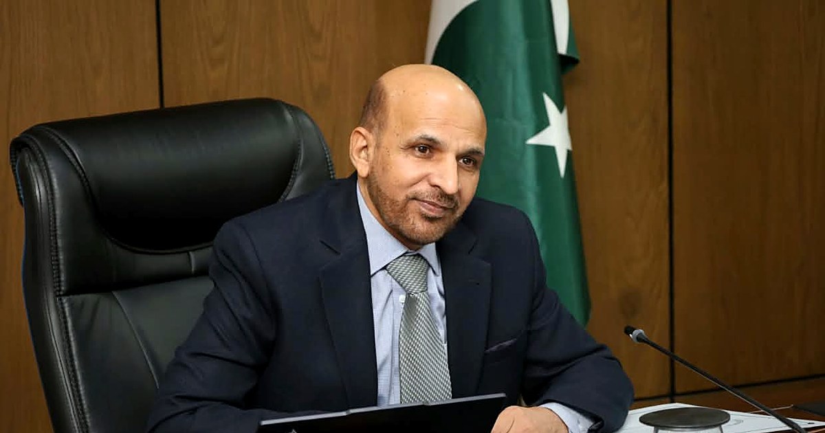 Zahid Asghar at his desk at the Pakistan Bureau of Statistics, with the national flag behind him